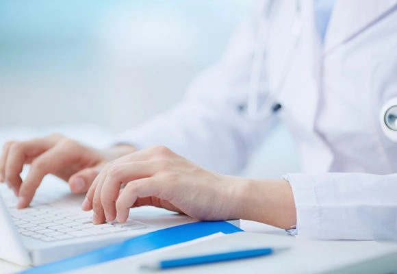 Doctor typing on laptop.
