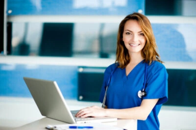 Smiling nurse using laptop.
